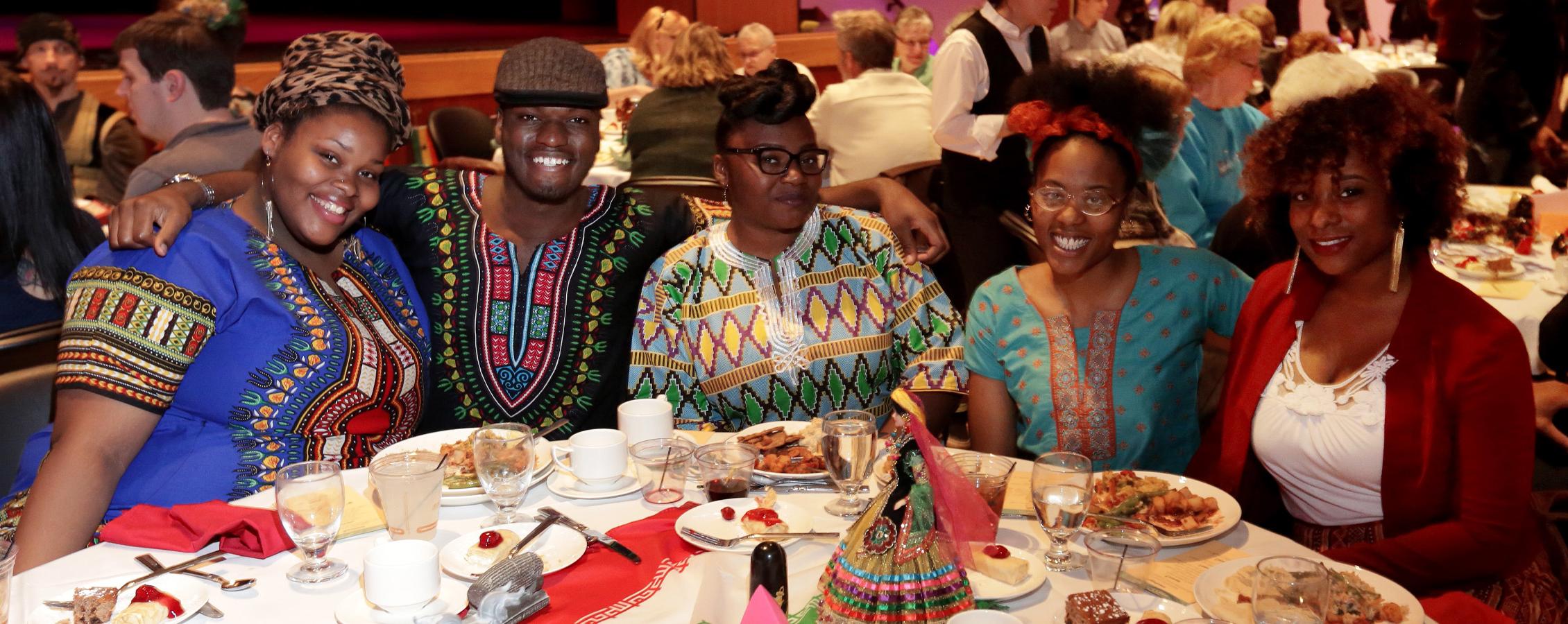 A group of international students group together at a banquet table and pose for a photo.